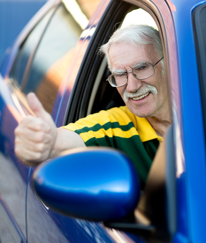 Happy man with thumbs up driving a car