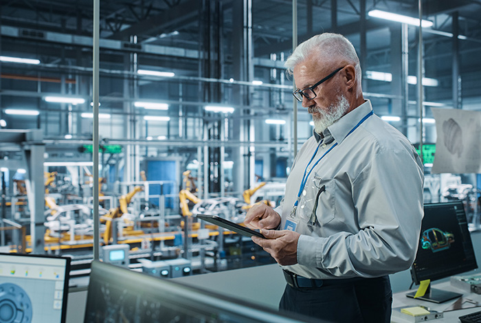 photo of a man looking at a tablet in a manufacturing facility