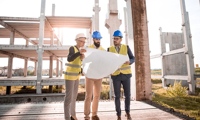 photo of 3 workers in construction outfits looking at a map on a construction site