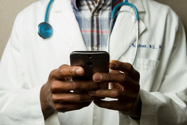 photo facing a doctor with their hands holding a phone