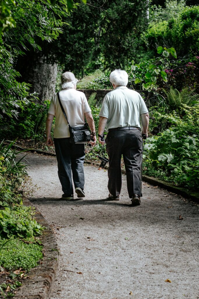 photo of tow elderly people walking along a path with their backs facing the camera